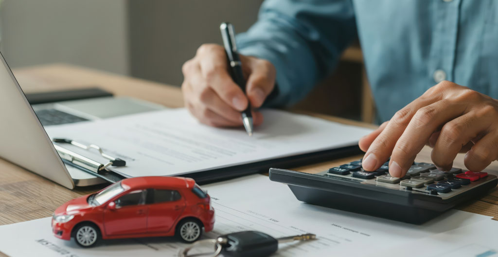 Documents de financement automobile, calculatrice et smartphone sur une table